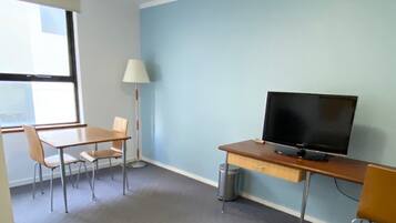 A room with a desk, a chair, a television, a lamp, and a window.