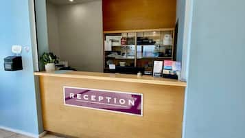 Un mostrador de recepción con un letrero que dice 'RECEPTION', una planta y una vitrina con objetos.