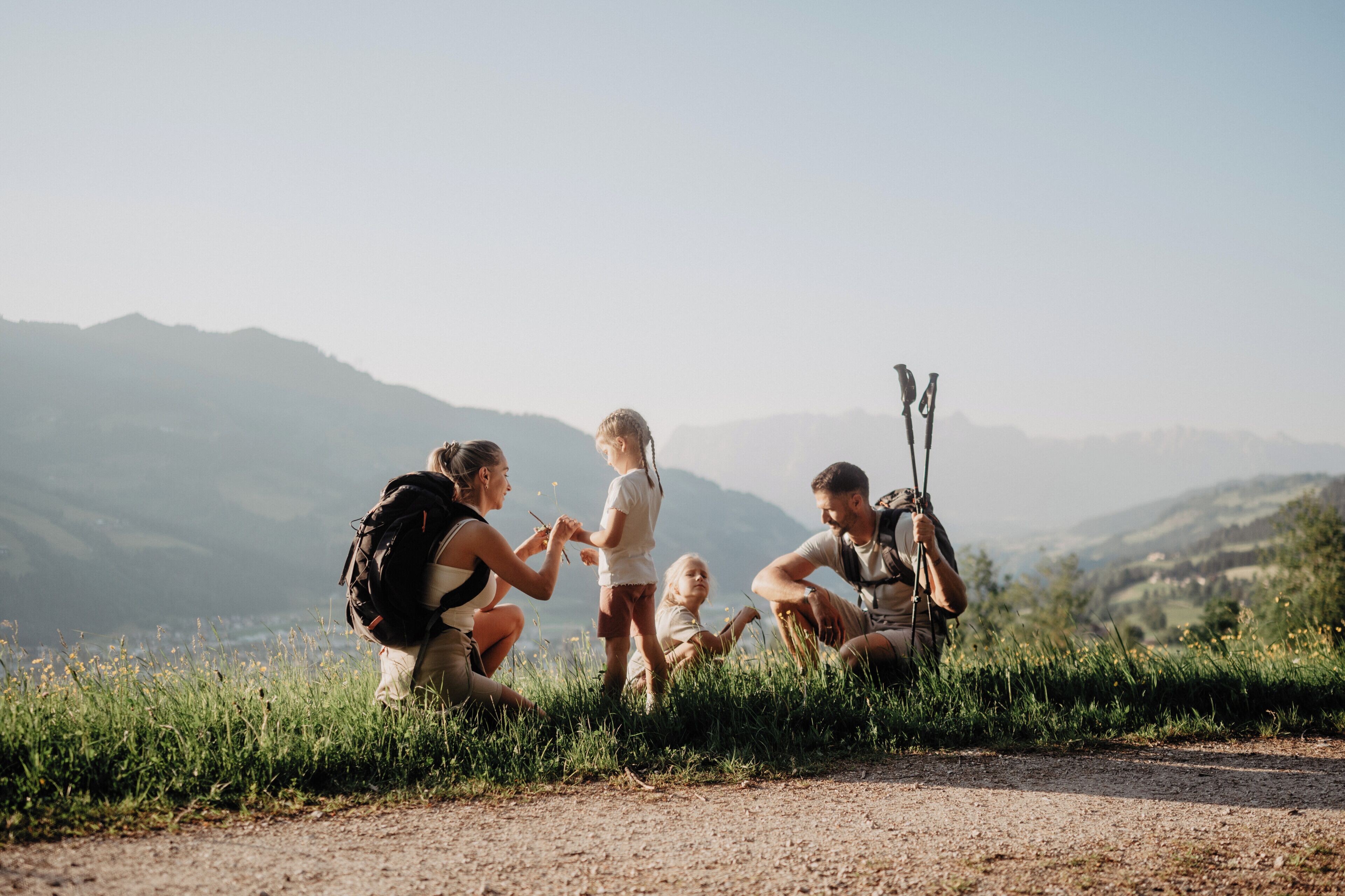 A group of people on a dirt path with mountains in the background.