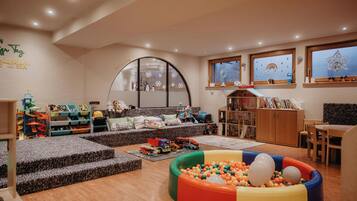 A children's playroom with a ball pit, play area, and seating.