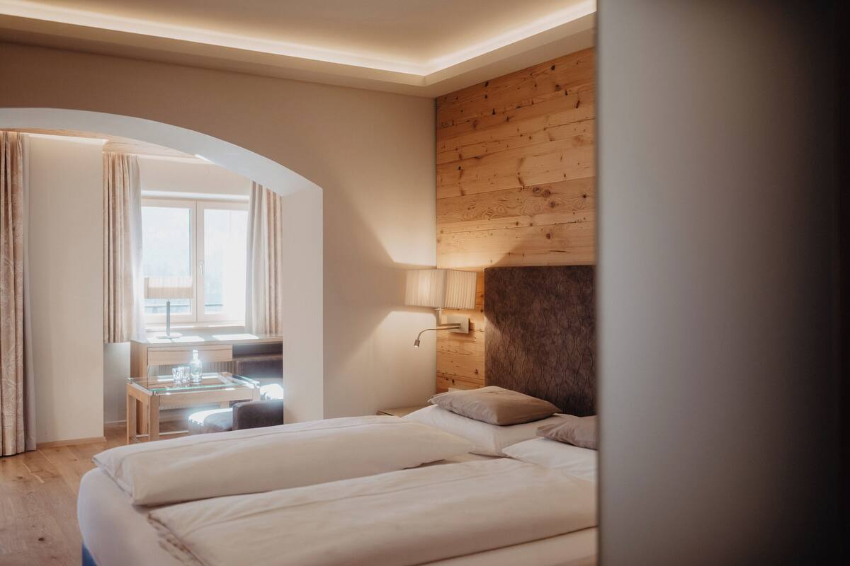 A hotel room with a bed, a desk, and a window.
