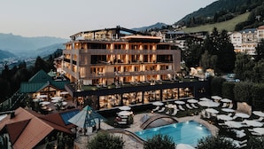 A multi-story hotel with outdoor seating and a swimming pool. -  Hotel Berghof | St. Johann in Salzburg (Sankt Johann im Pongau)