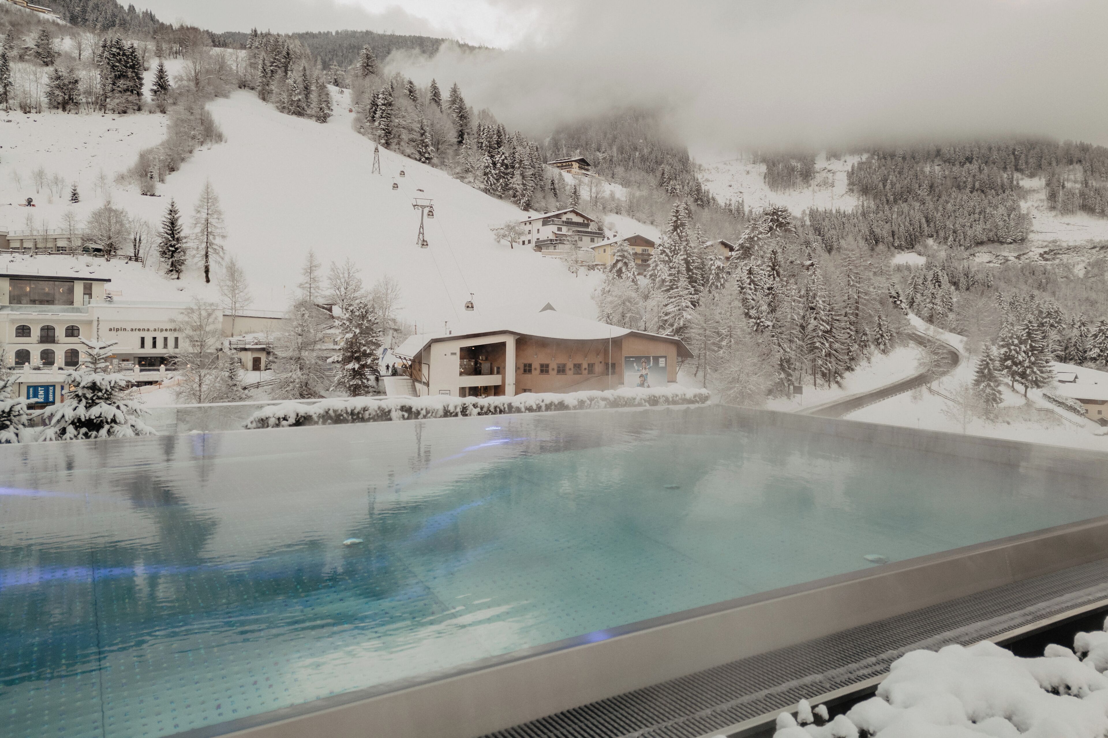 A swimming pool with a view of a snowy mountain and buildings in the background.