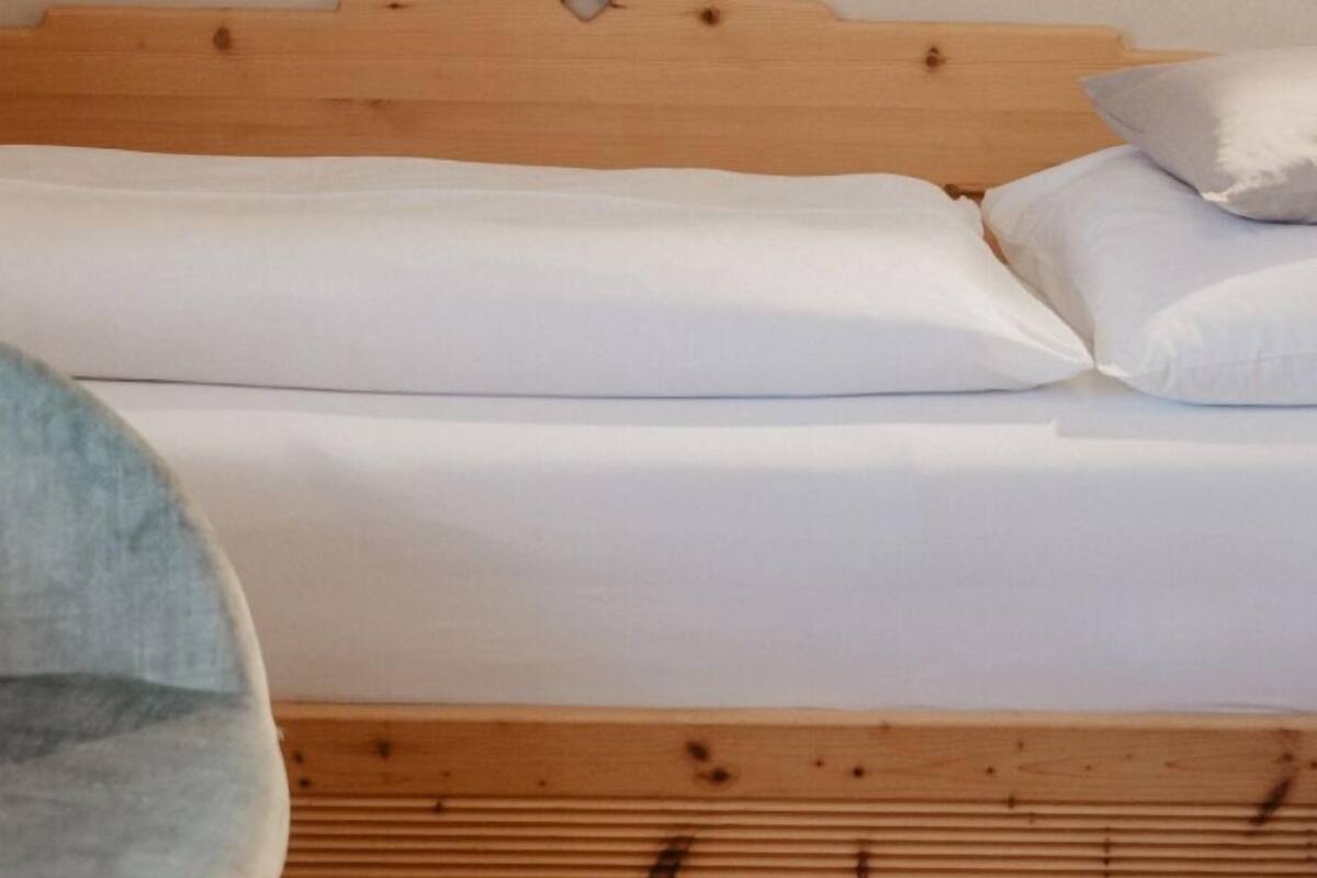 A bed with a wooden headboard and white bedding.