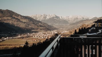 Un balcon offrant une vue sur des montagnes enneigées et sur une ville située en contrebas.