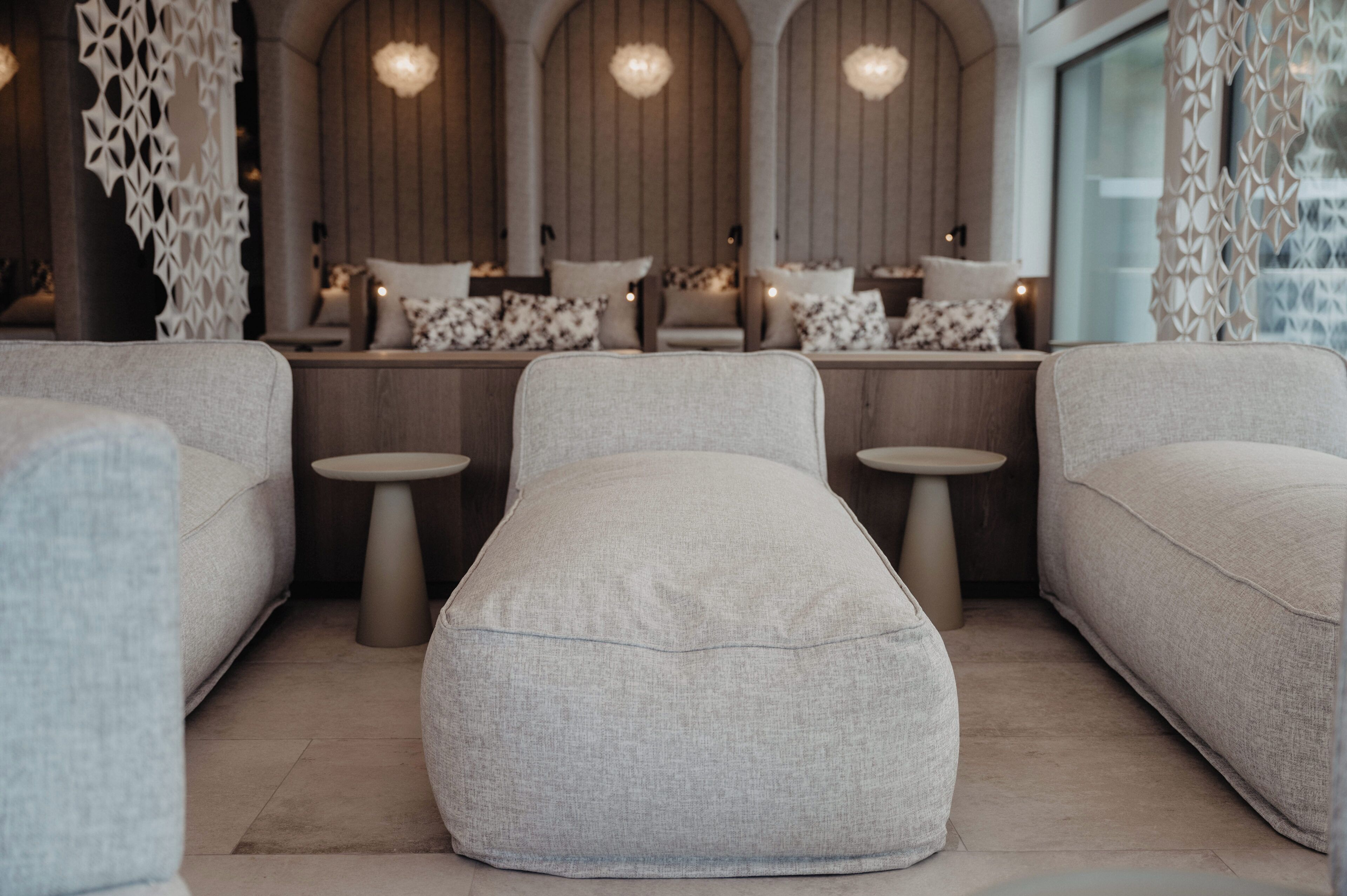 Un espace de détente moderne et minimaliste, comprenant un canapé, un pouf et de petites tables.