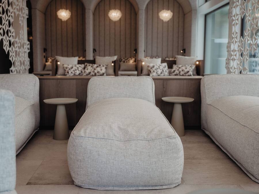 Un espace de détente moderne et minimaliste, comprenant un canapé, un pouf et de petites tables.