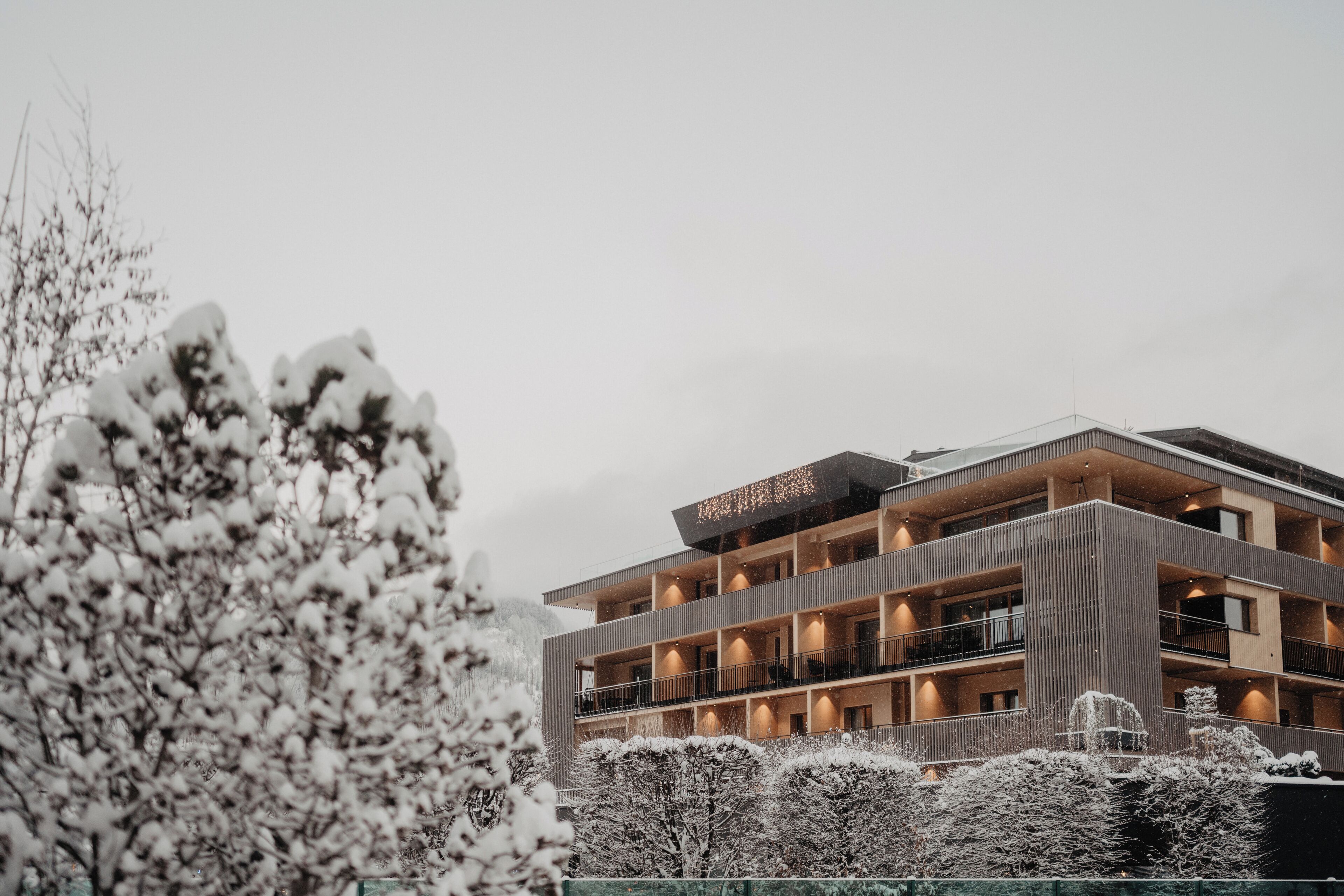 A multi-story hotel with a modern architectural design, featuring balconies and a rooftop terrace.