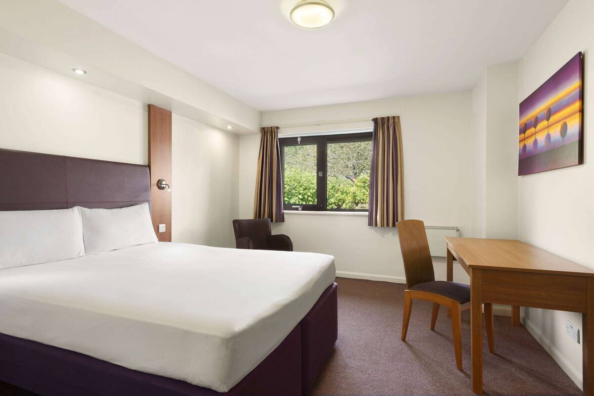 Une chambre d’hôtel avec un lit, un bureau et une chaise.