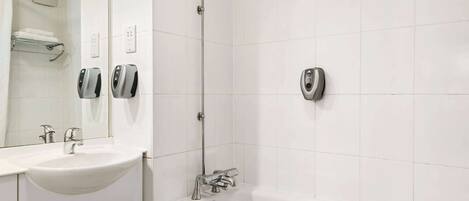 Un baño moderno con lavamanos, espejo y cabina de ducha.