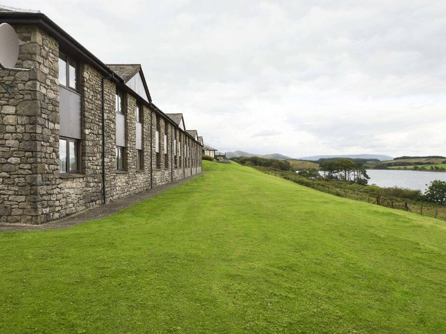 A stone building with a long, narrow lawn leading to a lake.