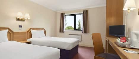 Habitación de hotel con dos camas, un escritorio con silla, televisor y ventana con cortinas.