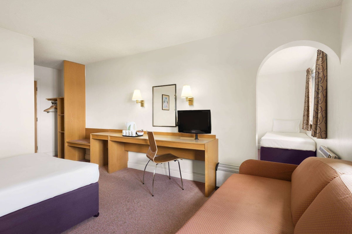 Une chambre d’hôtel comprenant un lit, un bureau avec une chaise, une télévision et un canapé.
