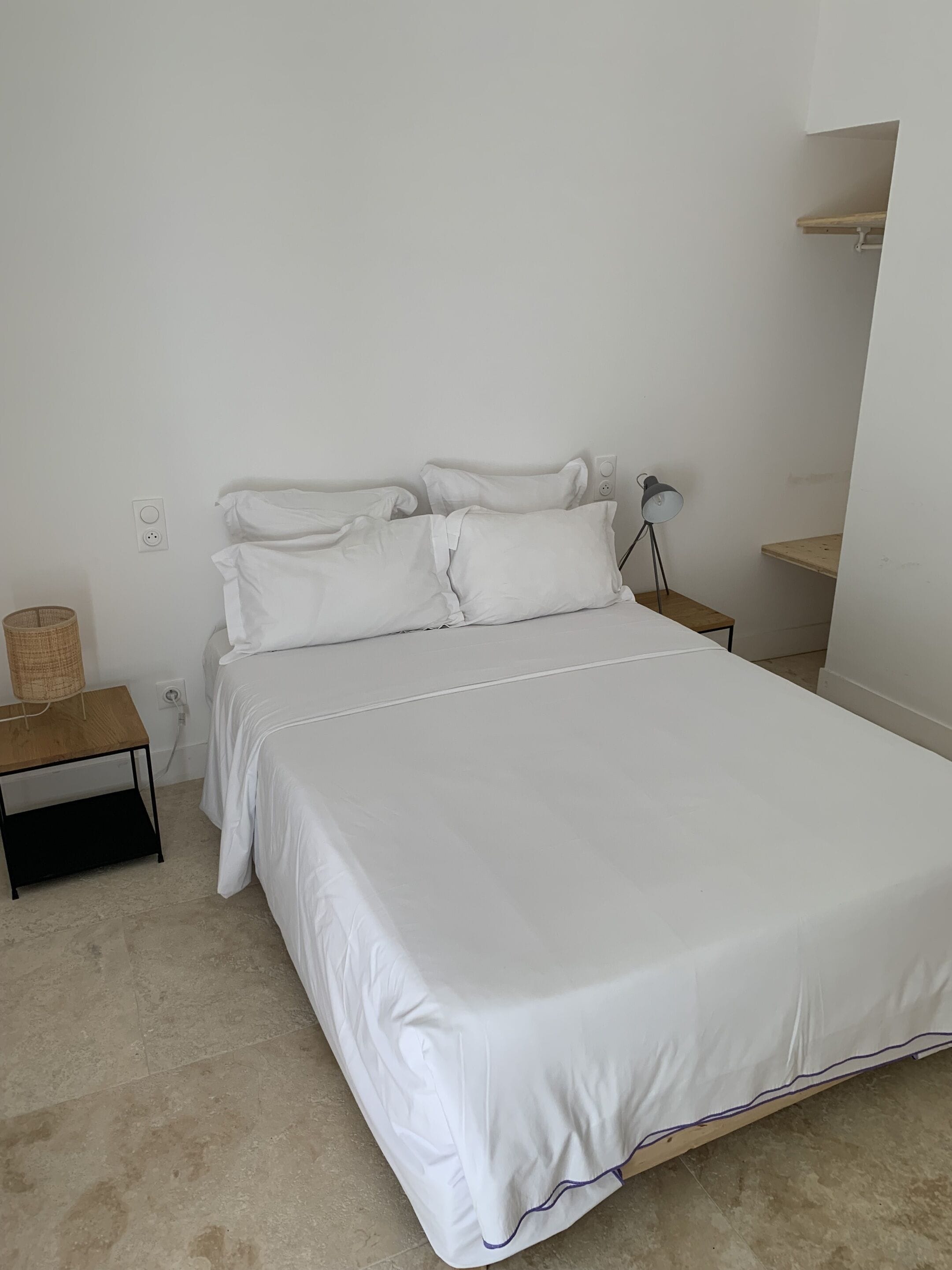 A neatly made bed with white bedding in a minimalistic room.