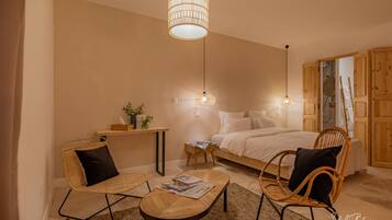 Ein gemütliches Schlafzimmer mit einem Bett, zwei Korbstühlen, einem kleinen Tisch und einer Pendelleuchte.
