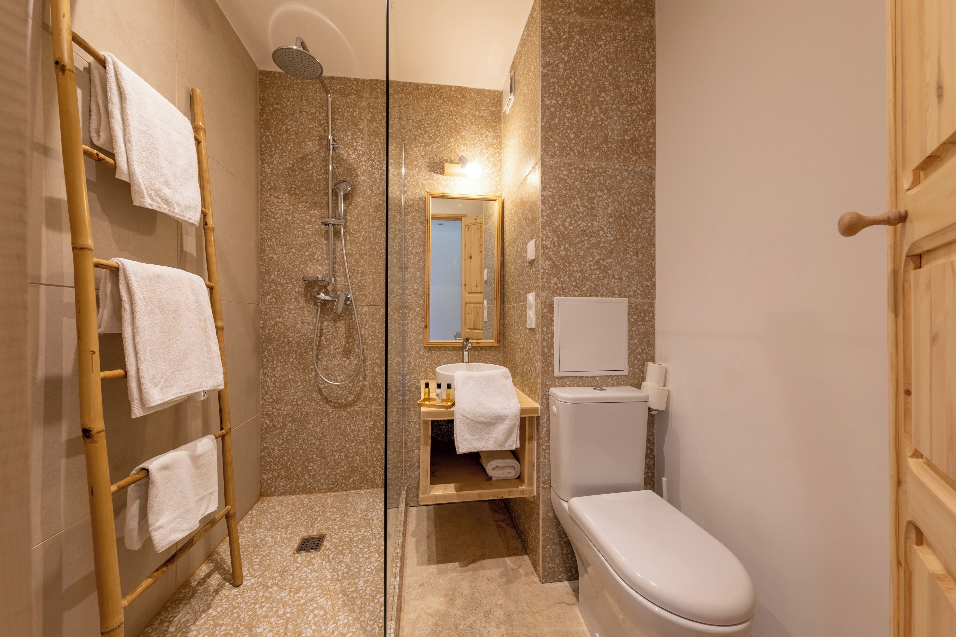 Un baño con ducha, inodoro y un perchero de madera.