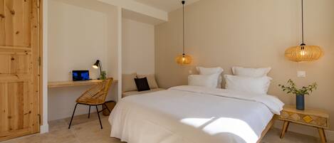 A bedroom with a large bed, a wooden desk, a chair, and two hanging lamps.