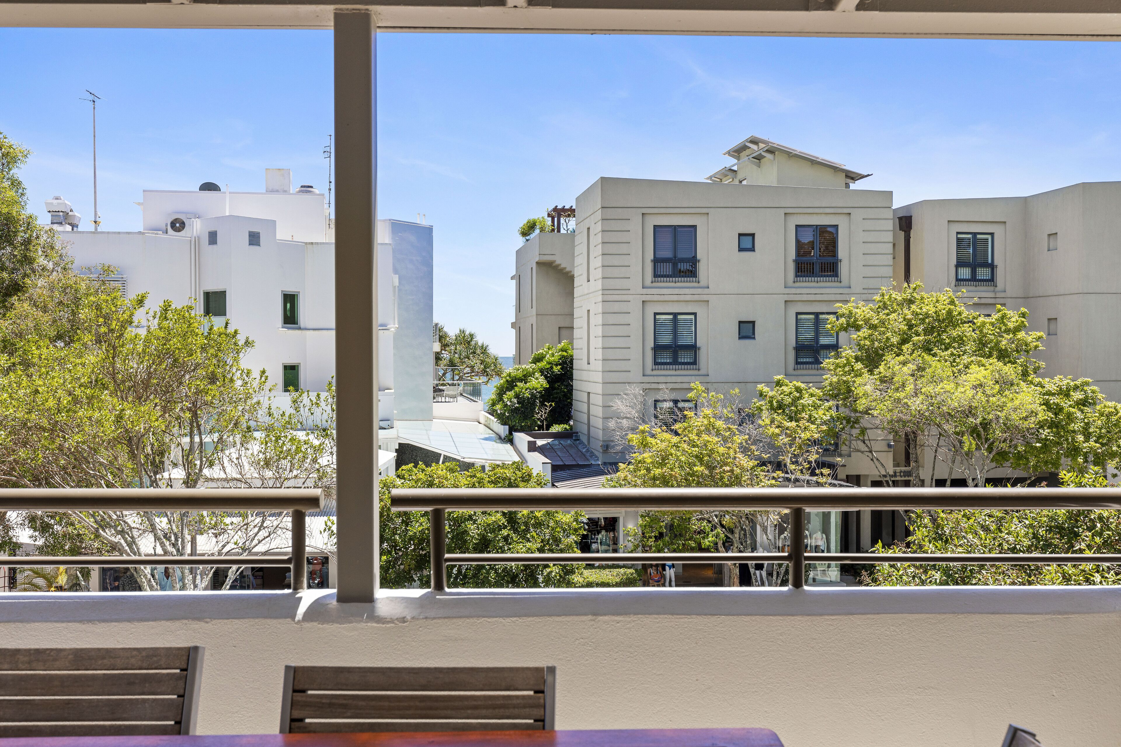 A balcony with a view of modern buildings and trees.