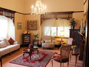 A traditional living room with a sofa, armchairs, a wooden cabinet, and a chandelier. - Dalfruin B&B (Bairnsdale)