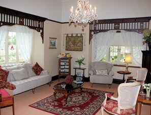 Een klassieke woonkamer met een bank, fauteuils, een bijzettafeltje en een kroonluchter.
