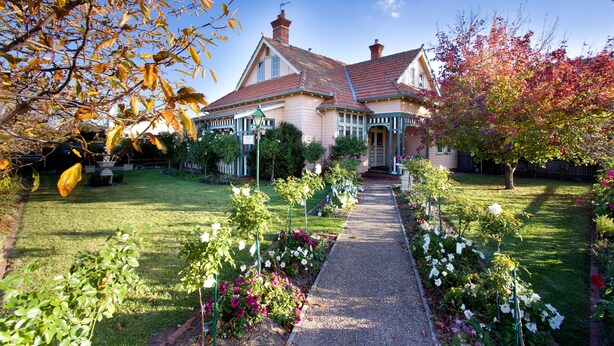 Une maison à deux étages avec un jardin et un chemin qui mène à la porte d’entrée.