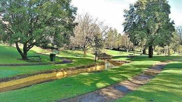A park with a paved path, benches, and trees.