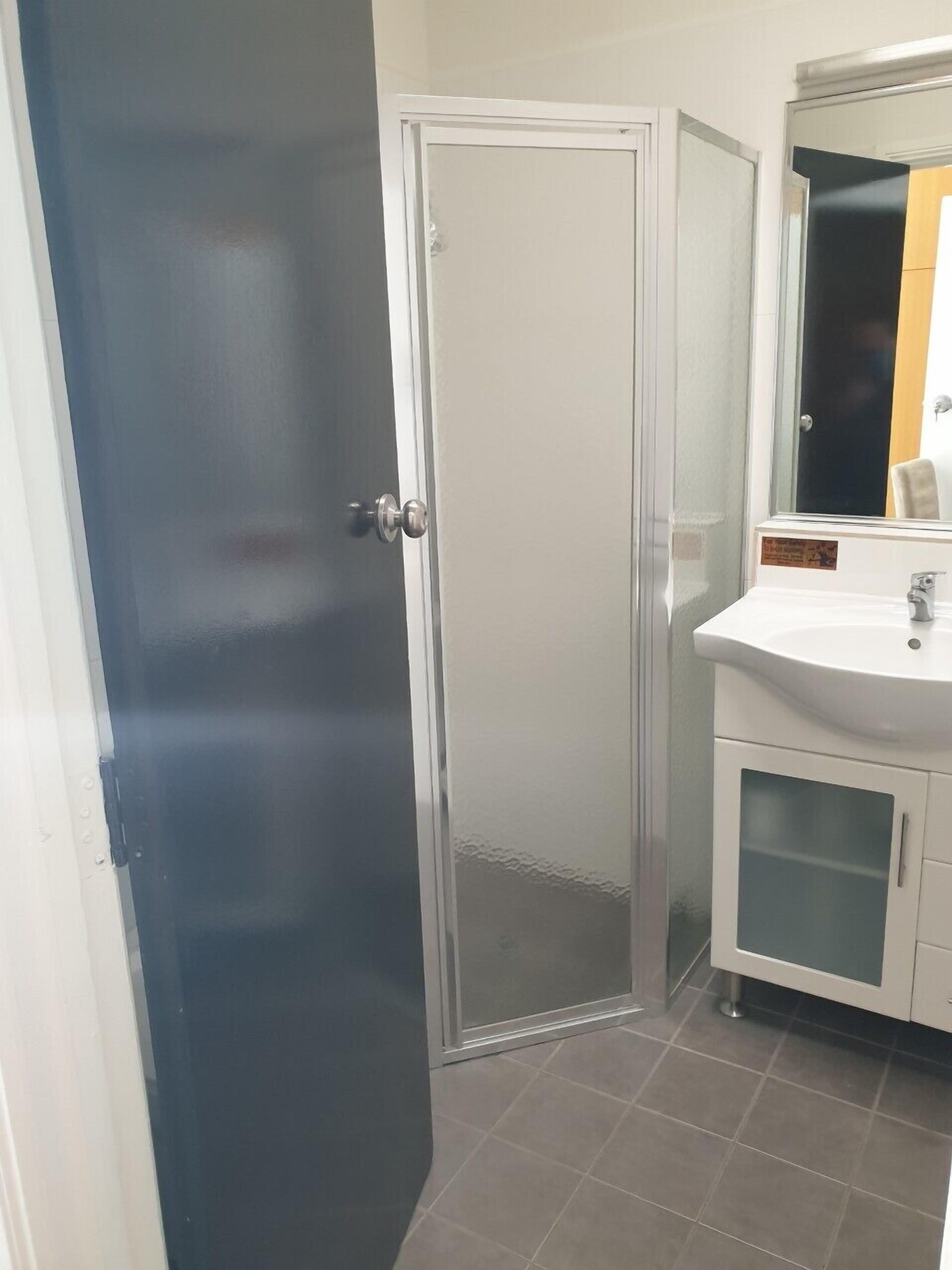 A bathroom with a white sink, a mirror, and a door.
