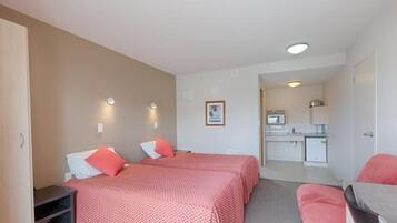 A hotel room with two beds, a kitchenette, and a small seating area.