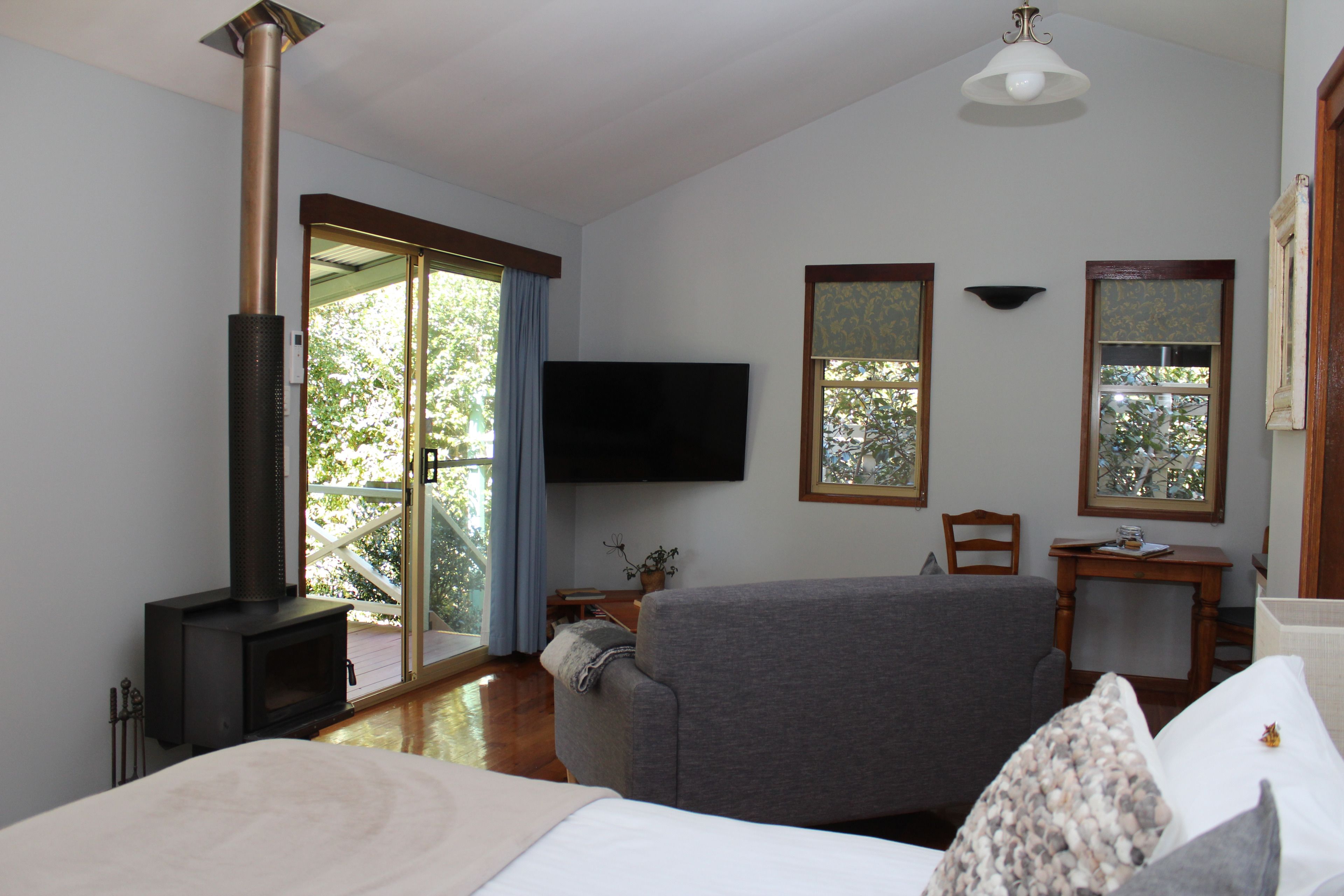 Una habitación con chimenea, cama, televisor y vistas al exterior.