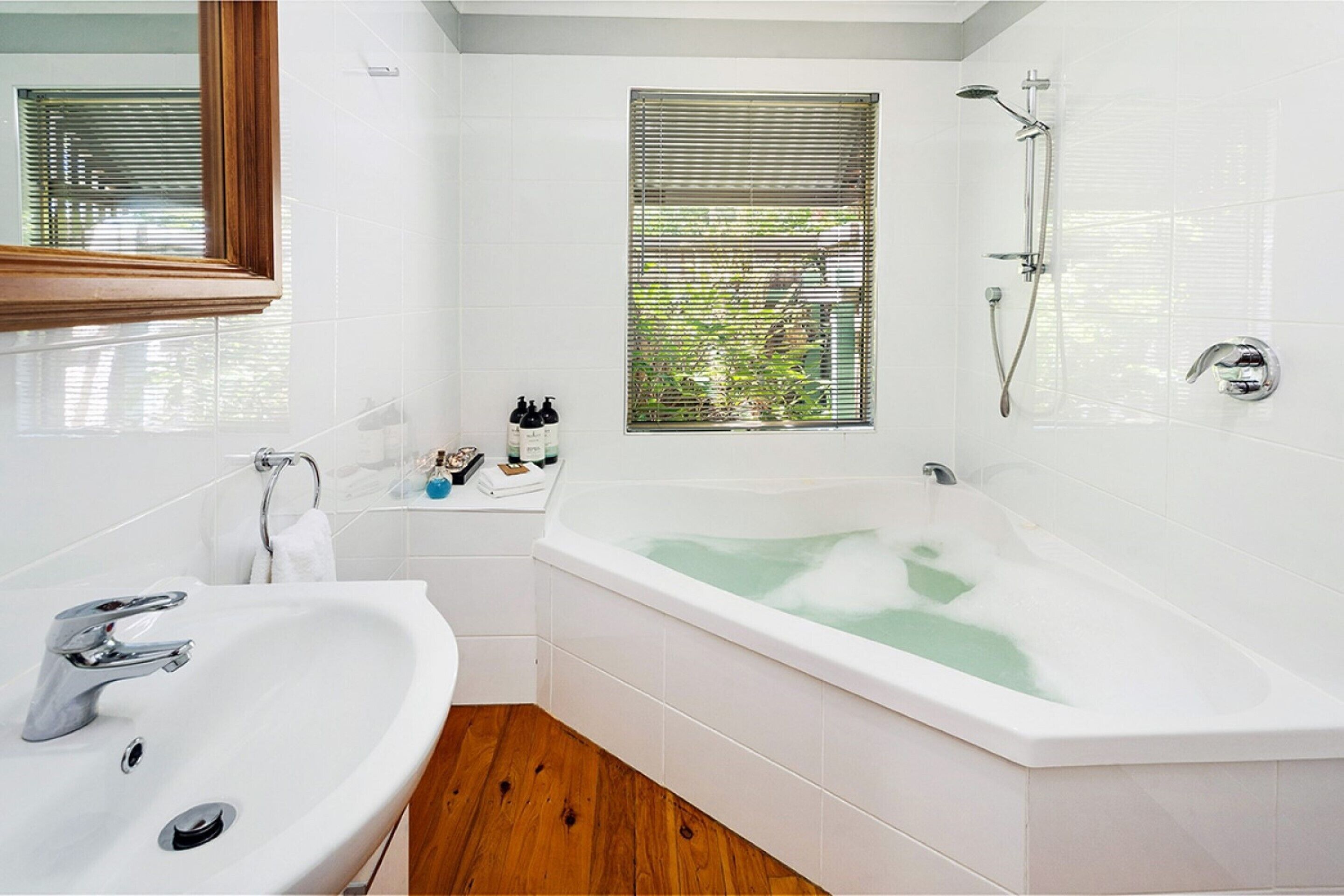 A modern bathroom with a freestanding bathtub, a vanity with a sink, and a window with blinds.