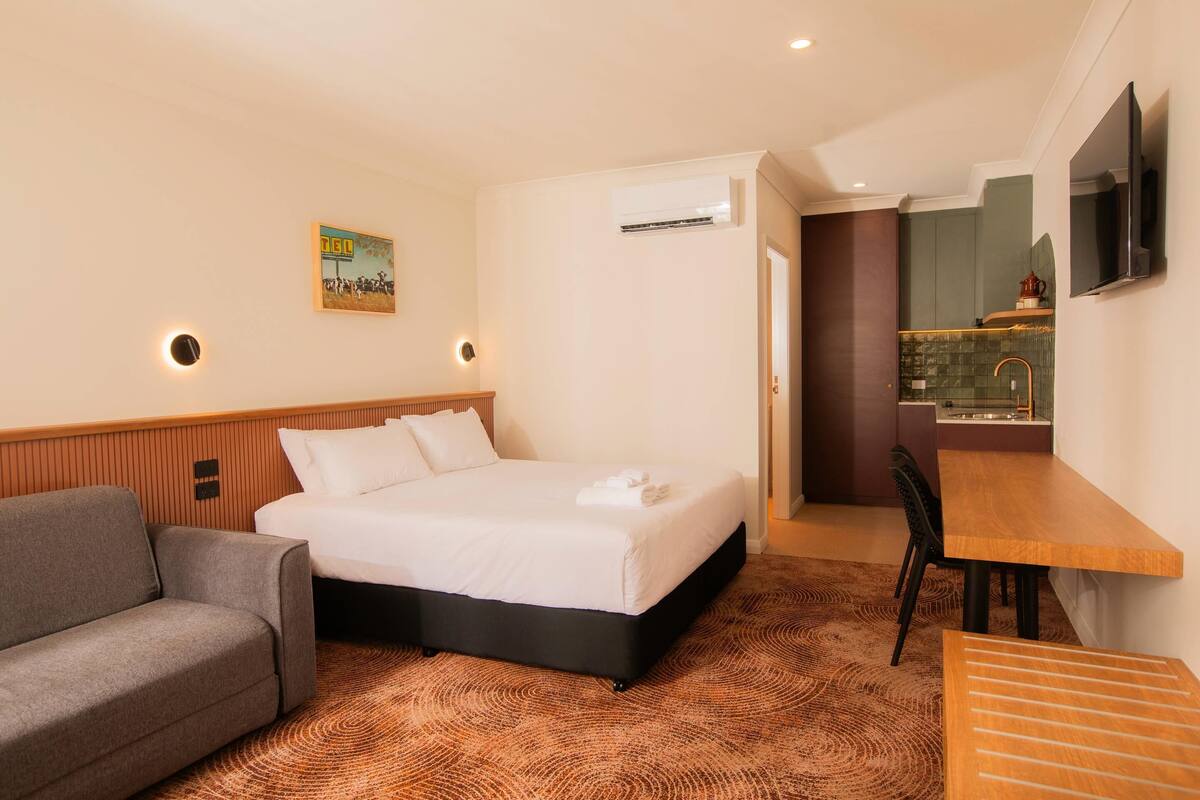 Una habitación de hotel con cama, sofá, escritorio y televisor.