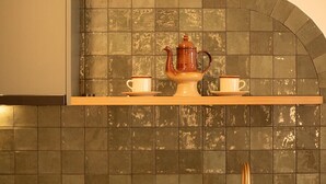 A kitchen with a stainless steel sink, a wooden shelf with a teapot and cups, and a tiled backsplash. - The Alluna Motel, an Ascend Collection Hotel (Armidale)