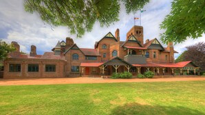 A large, historic brick building with multiple chimneys, a prominent tower, and a covered porch. - The Alluna Motel, an Ascend Collection Hotel (Armidale)