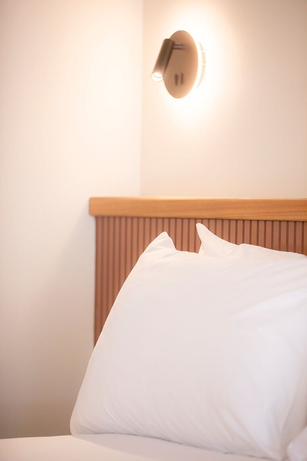 Un lit bien fait, avec une literie blanche et une tête de lit en bois.