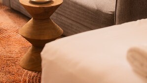 A hotel room with a grey sofa, a wooden side table with a cup, and a patterned carpet. - The Alluna Motel, an Ascend Collection Hotel (Armidale)