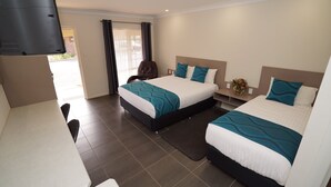 Une chambre d’hôtel avec deux lits, un bureau et une télévision.
