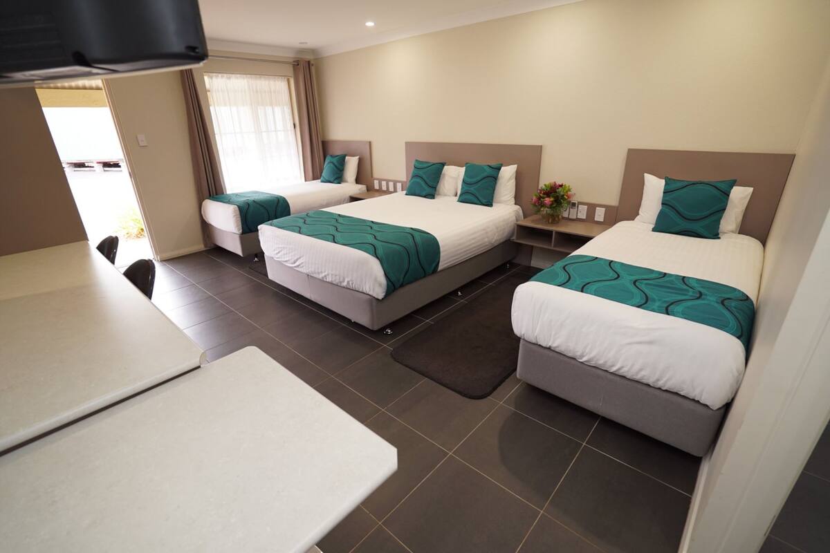 A hotel room with two single beds, a small table, and a sofa.