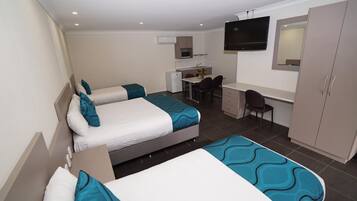 A hotel room with two beds, a desk, a chair, a TV, and a wardrobe.