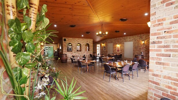 Un restaurant aux murs en briques, au plafond en bois et aux tables accompagnées de chaises.