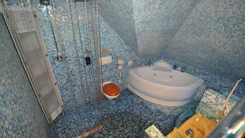 Un baño con bañera, inodoro y zona de ducha con puerta de cristal.