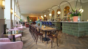 Un amplio vestíbulo de hotel con una larga recepción, varias zonas de estar y un bar.