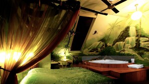 Una habitación con una cama grande, una bañera de madera y un mural de una cascada.