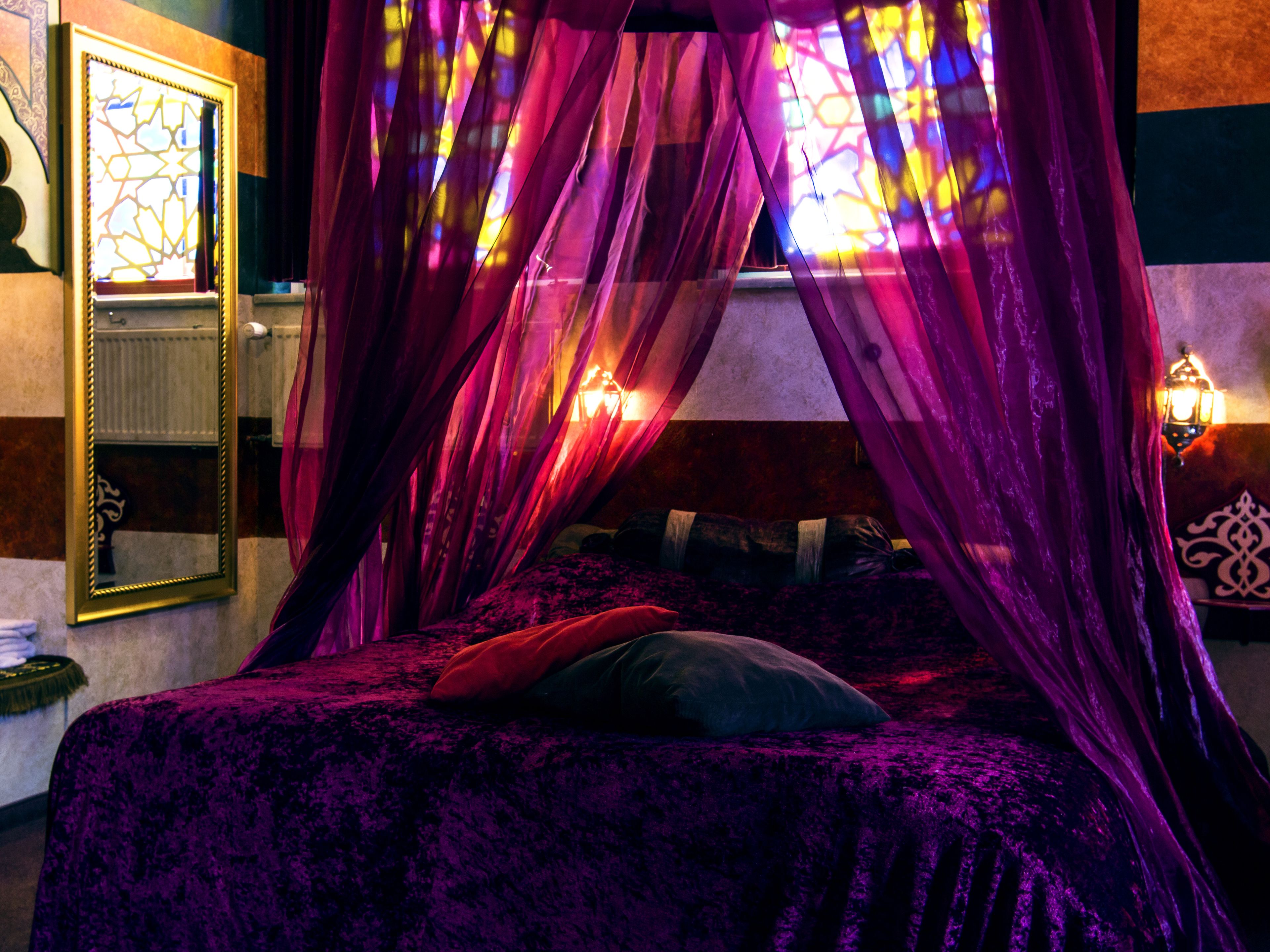 Ein Zimmer mit einem Bett, einem Spiegel und einer Wandleuchte.