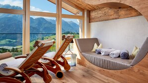 A room with large windows, wooden furniture, and a view of mountains. - Hotel Tirol (Fiss)