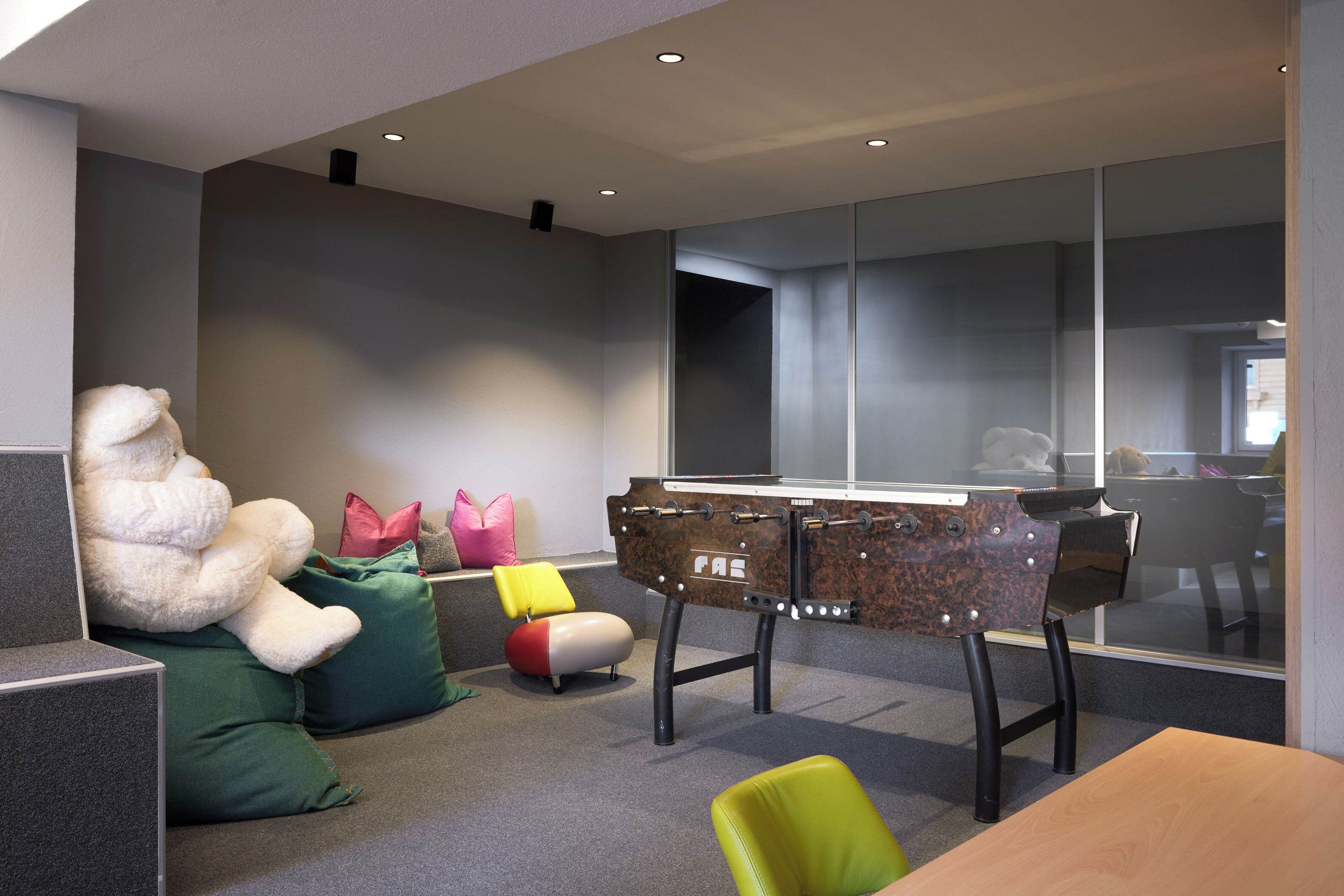 Un espace de bureau moderne, doté de cloisons, d’une table de baby-foot et de sièges confortables.