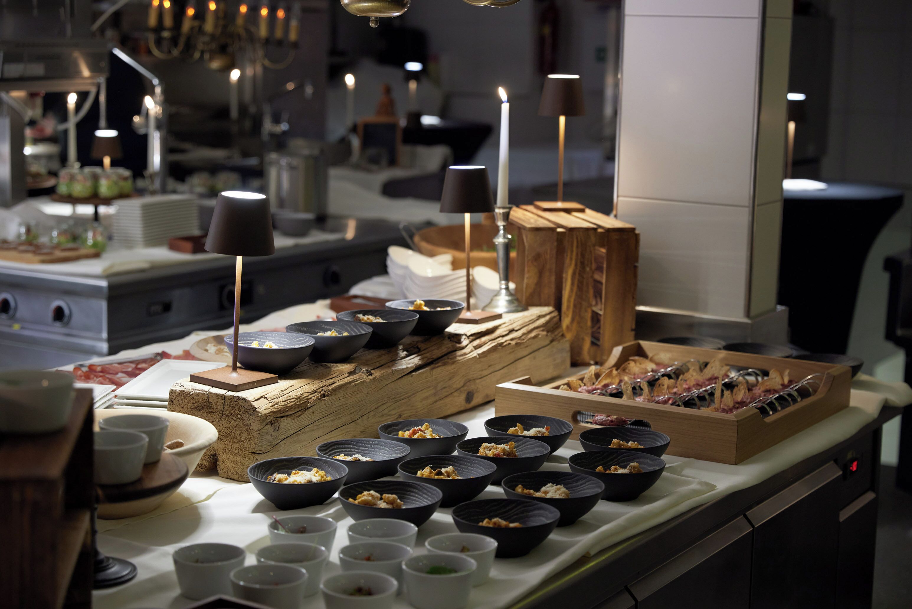Un comedor con varios cuencos negros sobre una mesa, velas y un bloque de madera.