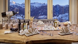 A dining table set for a meal with a mountain view through large windows. - Hotel Tirol (Fiss)
