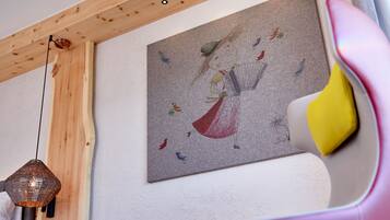 Una habitación con techo de madera, una obra de arte en la pared que representa un pavo real y pájaros, y una lámpara colgante.