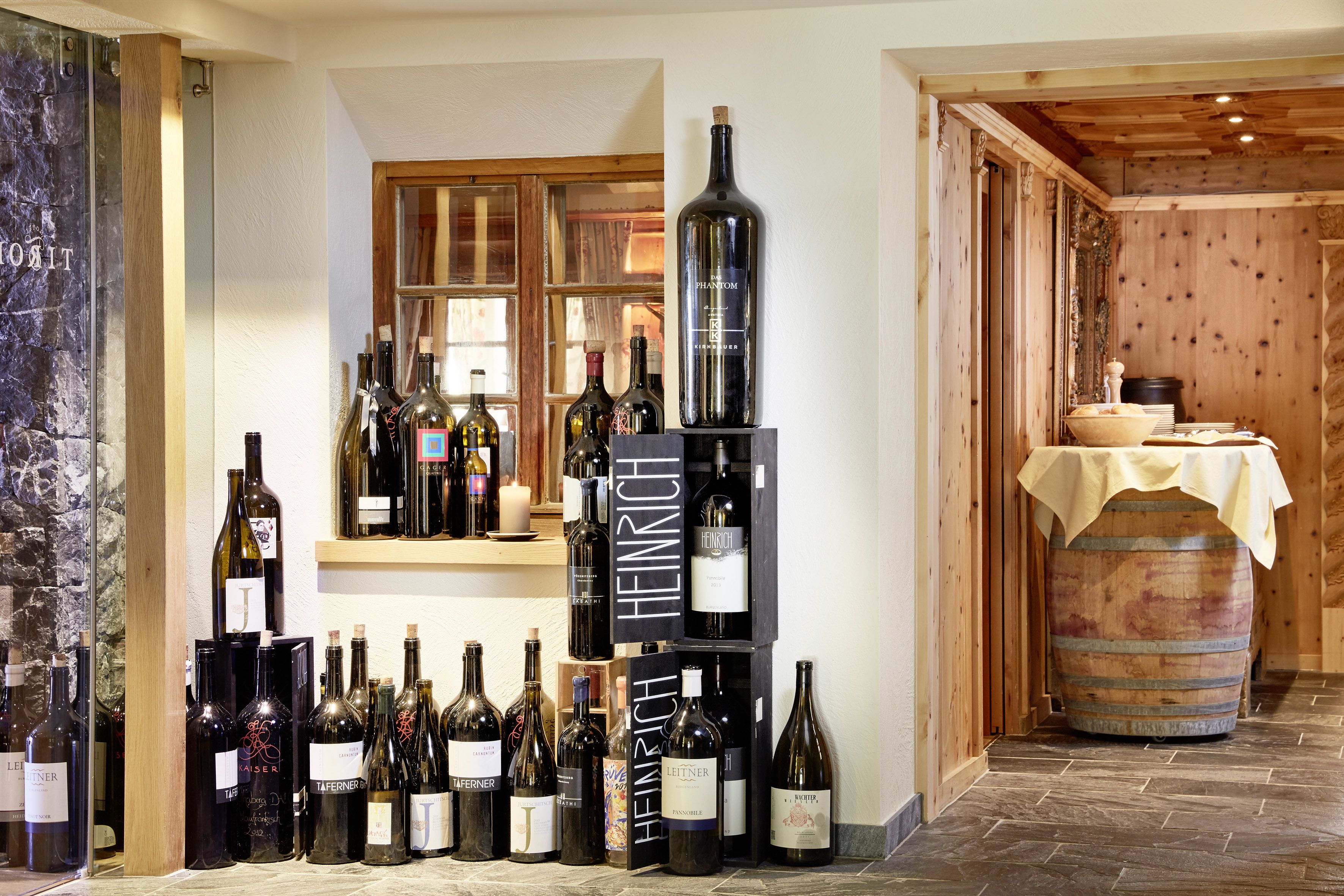 A wine cellar with numerous wine bottles on shelves and a wooden barrel.