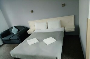 A hotel room with a bed, a chair, and a nightstand. - Excelsior Motor Inn (Port Macquarie)